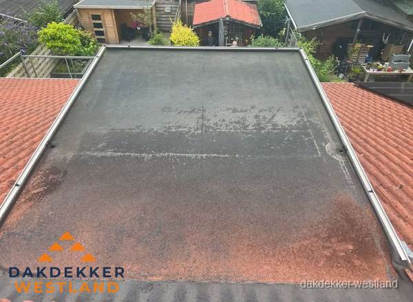 Verouderd plat dak met slijtage tussen schuine daken in Westland Verouderd plat dak met slijtage tussen schuine daken in Westland