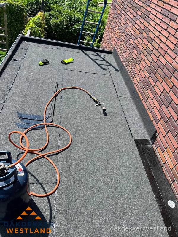 Plat dak met bitumen en brandgereedschap van dakdekkersbedrijf in Westland