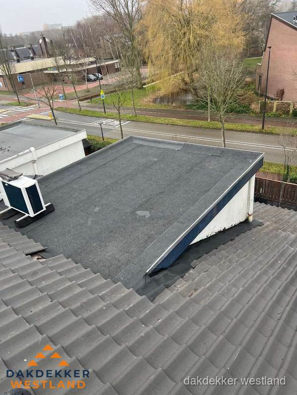Plat dak met bitumen dakbedekking naast schuin pannendak in Westland