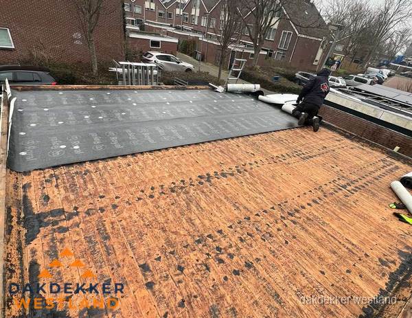Dakdekker legt onderlaag op plat dak met houten constructie in Westland