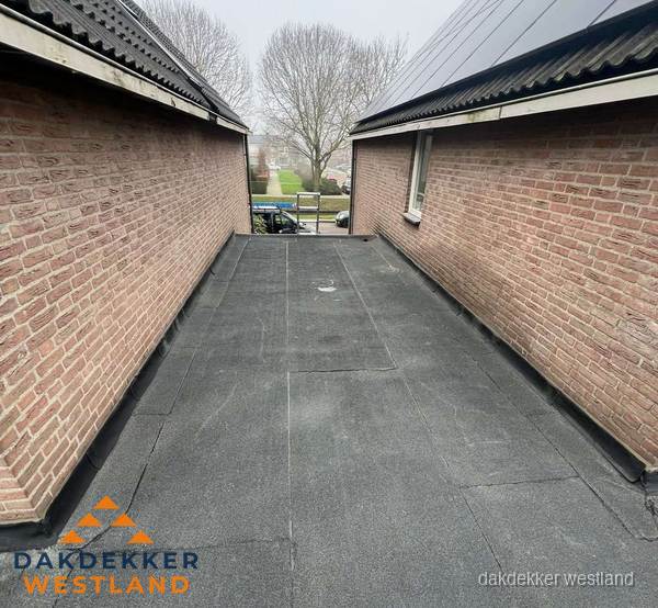 Plat dak met bitumen dakbedekking tussen bakstenen muren in Westland Plat dak met bitumen dakbedekking tussen bakstenen muren in Westland